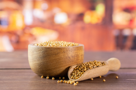 Lot of whole white mustard seeds with wooden bowl and wooden scoop in a rustic kitchenの写真素材