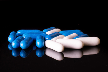 Lot of whole blue and white sweet licorice comfit isolated on black glass