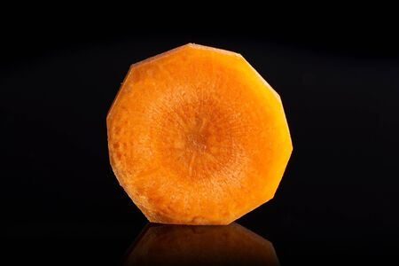 One half of fresh orange carrot isolated on black glass