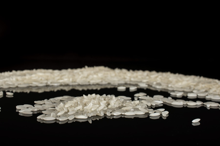 Lot of whole white jasmine rice grains isolated on black glass