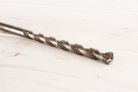 One whole metal drill work item on white wood