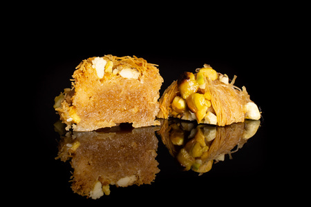 Group of two halves of sweet lebanese baklava piece bird nest variety isolated on black glass