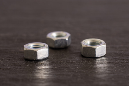 Group of three whole metal locking nuts work item on grey stone