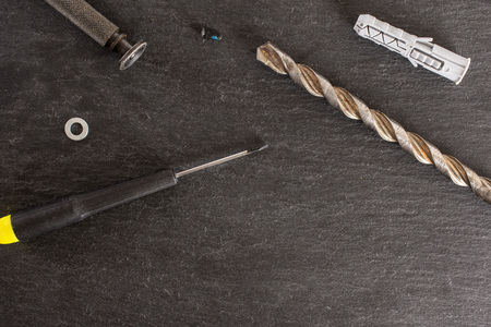 Lot of whole work item screwdrivers, drill, wall plug flatlay on grey stone