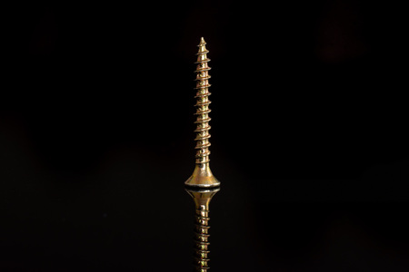 One whole sharp golden screw work item isolated on black glassの写真素材