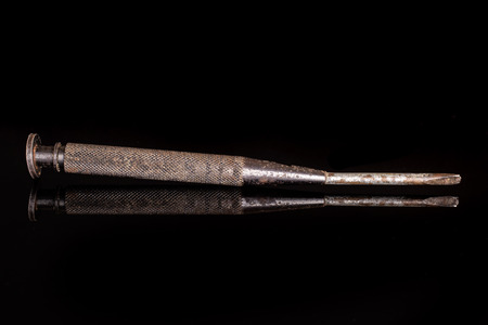 One whole rusty metal turnscrew work item isolated on black glass