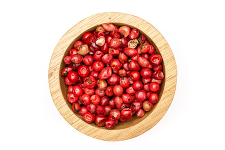 Lot of whole peruvian pink pepper in a wooden bowl flatlay isolated on white backgroundの写真素材