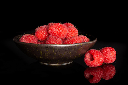 Lot of whole sweet fresh red raspberry on grey ceramic plate isolated on black glassの写真素材