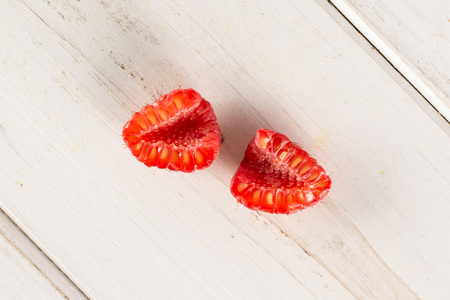 Group of two halves of fresh red raspberry cross section flatlay on white woodの写真素材