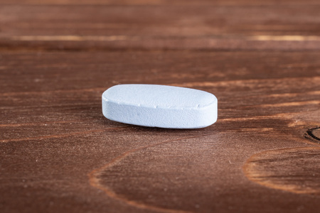 One whole blue medical drug on brown woodの写真素材