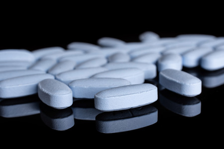 Lot of whole blue medical drug isolated on black glassの写真素材