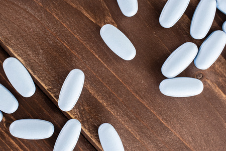 Lot of whole blue medical drug uncoated flatlay on brown woodの写真素材