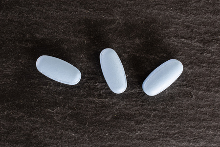 Group of three whole blue medical drug flatlay on grey stone