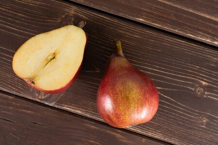 Group of one whole one half of fresh dark red pear anjou flatlay on brown wood