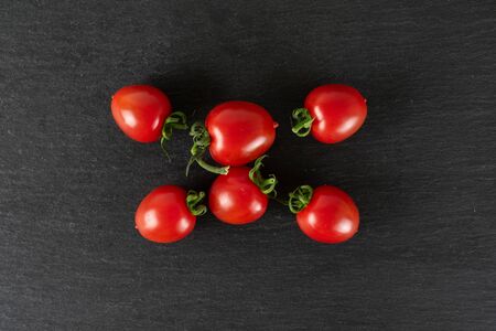 Group of six whole fresh red tomato cherry flatlay on grey stoneの写真素材