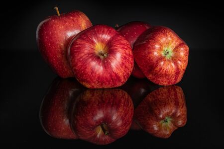 Group of four whole fresh apple red delicious isolated on black glassの写真素材
