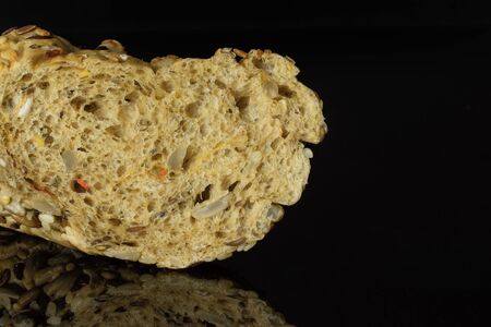 Closeup of one half of fresh cereal baguette isolated on black glassの写真素材