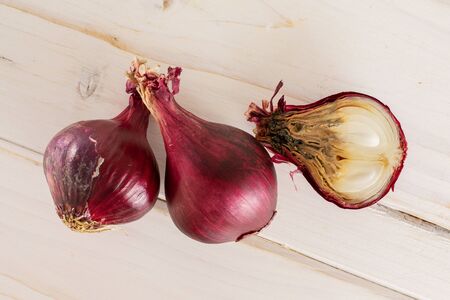 Group of two whole one half of stale red onion flatlay on white woodの写真素材