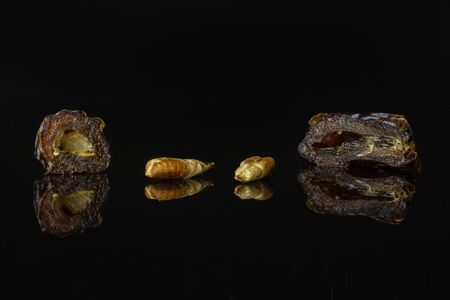 Group of two halves two pieces of dried brown date medjool isolated on black glass