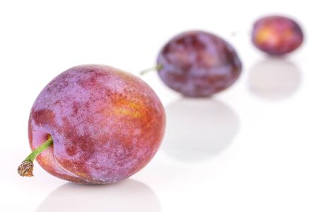 Group of three whole fresh blue plum placed diagonally in line isolated on white backgroundの写真素材