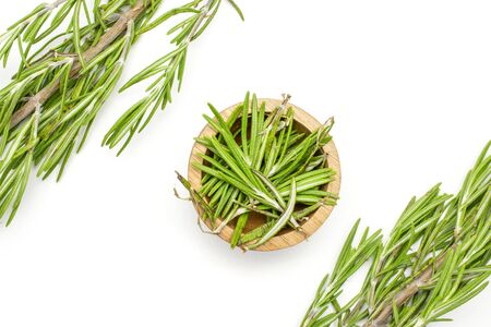 Group of two whole lot of pieces of fresh evergreen sprig of rosemary in a wooden bowl flatlay isolated on white backgroundの写真素材