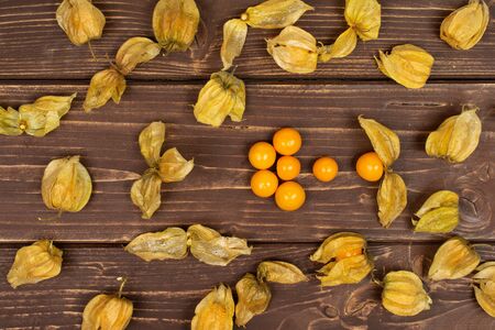 Lot of whole lot of pieces of fresh orange physalis flatlay on brown woodの写真素材