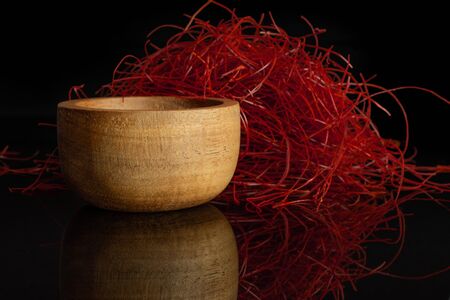 Lot of whole red chili pepper threads in wooden bowl isolated on black glassの写真素材