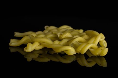 Lot of whole raw pasta gemelli isolated on black glass