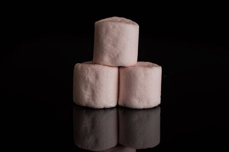 Group of three whole pink sweet fluffy marshmallow isolated on black glass