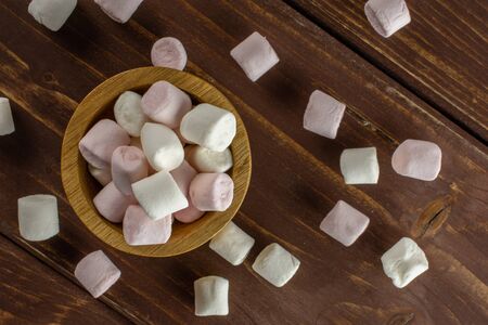 Lot of whole sweet fluffy marshmallow in wooden bowl flatlay on brown woodの写真素材