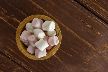 Lot of whole sweet fluffy marshmallow copyspace in wooden bowl flatlay on brown woodの写真素材
