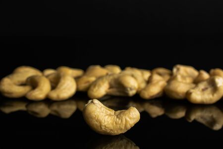Lot of whole unsalted beige cashew isolated on black glassの写真素材