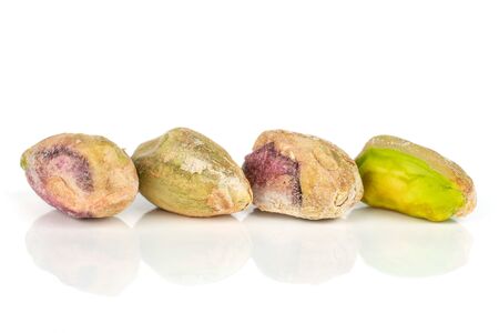 Group of four whole ripe green pistachio in closeup in row isolated on whiteの写真素材