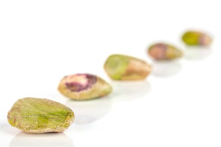 Group of five whole ripe green pistachio in closeup placed diagonally in line isolated on whiteの写真素材