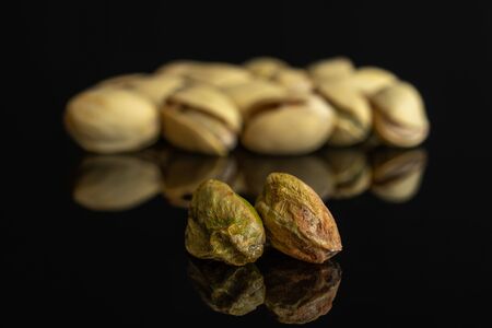Lot of whole ripe green pistachio in closeup isolated on black glassの写真素材