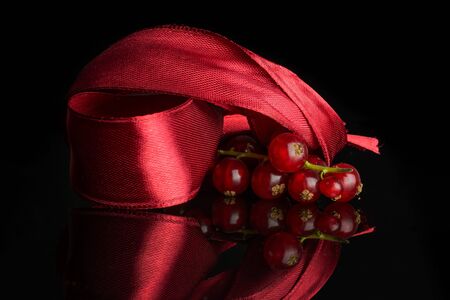 Lot of whole fresh red currant with red ribbon isolated on black glassの写真素材