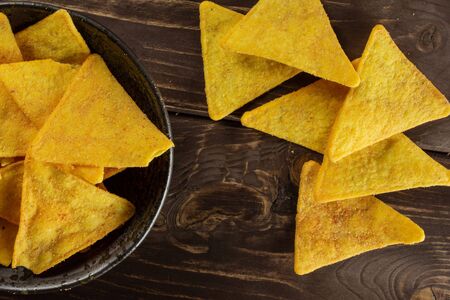 Lot of whole crispy cheese tortilla chips on grey ceramic plate flatlay on brown wood