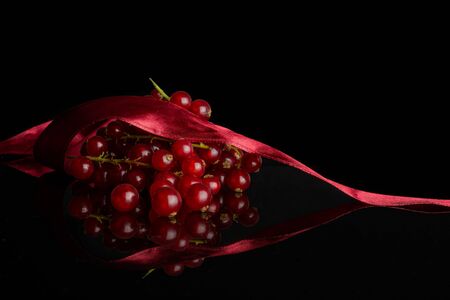 Lot of whole fresh red currant with red ribbon isolated on black glassの写真素材