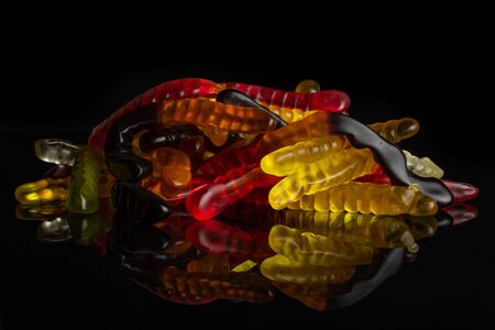 Lot of whole colourful jelly worm candy stack isolated on black glassの写真素材