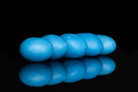 Group of five whole blue sugared nut dragee in row isolated on black glassの写真素材