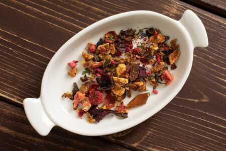 Lot of pieces of lavender strawberry ice tea in ceramic stewpan flatlay on brown woodの写真素材