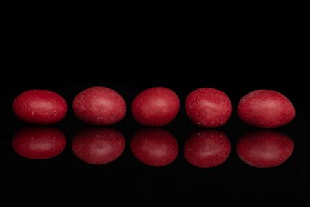 Group of five whole red sugared nut dragee isolated on black glassの写真素材