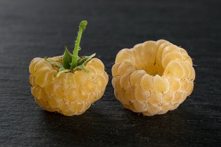 Group of two whole fresh golden hymalayan raspberry on grey stone