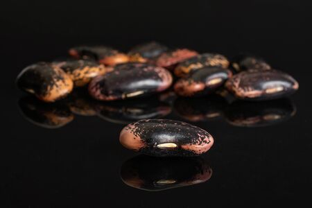 Lot of whole stained purple bean one is in the front isolated on black glassの写真素材