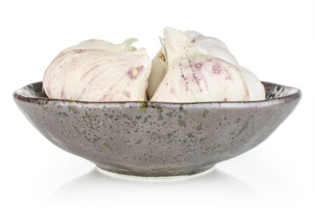 Group of four whole organic white garlic allium sativum in dark ceramic bowl isolated on white backgroundの写真素材