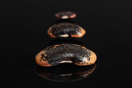 Group of three whole stained purple bean isolated on black glassの写真素材