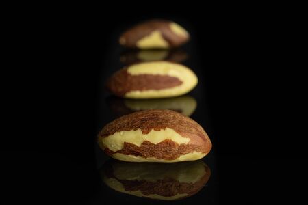 Group of three whole raw brown brazil nut isolated on black glassの写真素材