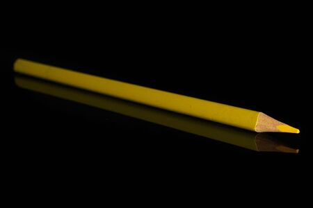 One whole yellow colored pencil isolated on black glass