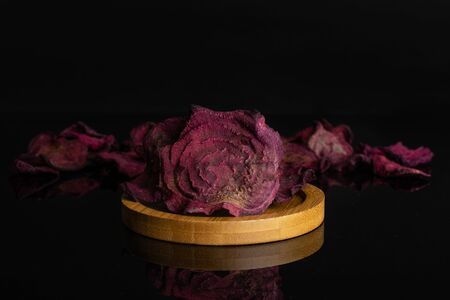 Lot of slices of dried red beetroot on bamboo coaster isolated on black glassの写真素材