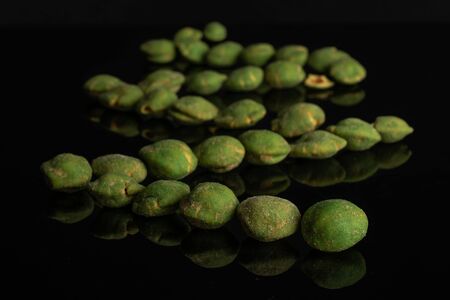 Lot of whole spicy green wasabi peanut isolated on black glassの写真素材